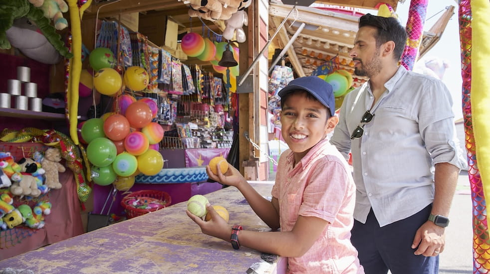 Father and son trying to knock down cans at a funfair